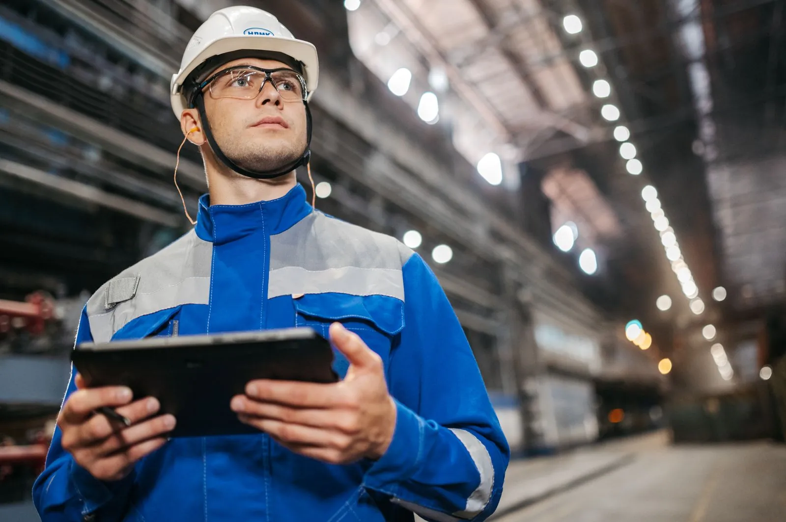 Site manager wearing a safety helmet checks system data on a tablet